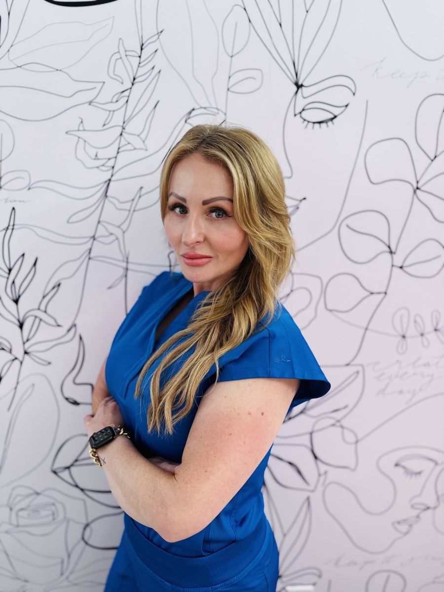 Paige Gumm in royal-blue scrubs in front of the line-art face mural in her Longview studio